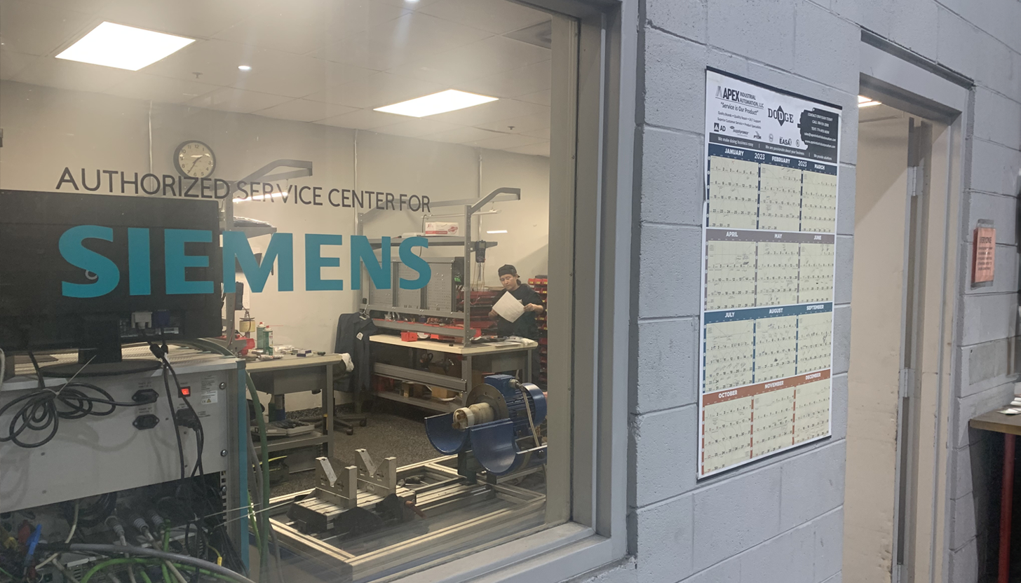 View into the Siemens Authorized Service Center laboratory at Apex Industrial Automation, showcasing the Siemens logo on the window.