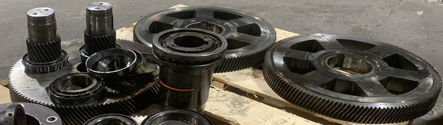 Large gears and gearbox components on a wooden pallet at Apex Industrial Automation, post-disassembly.