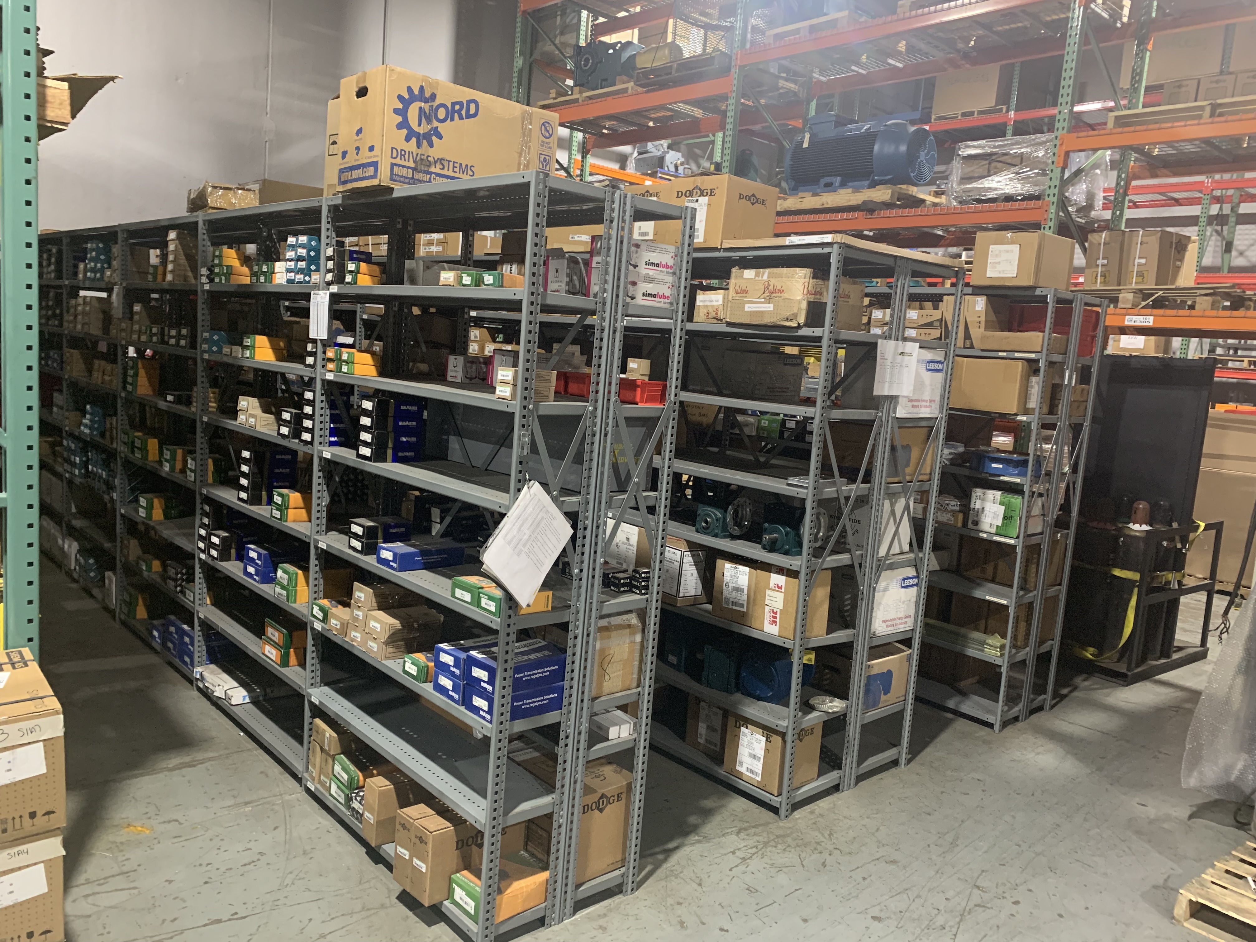 Interior view of Apex Industrial Automation's warehouse with rows of shelves stocked with components ready for industrial parts distribution and repairs.
