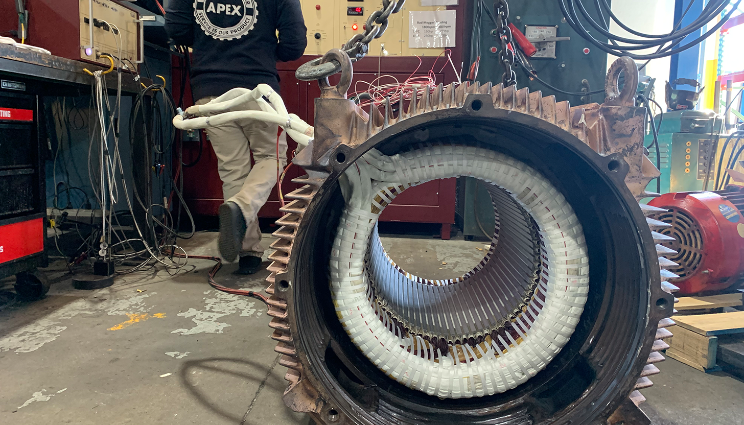 Repaired large electric motor at Apex Industrial Automation, with neatly wound packings and a technician using a Phenix MTS D-Series Test Panel in the background.