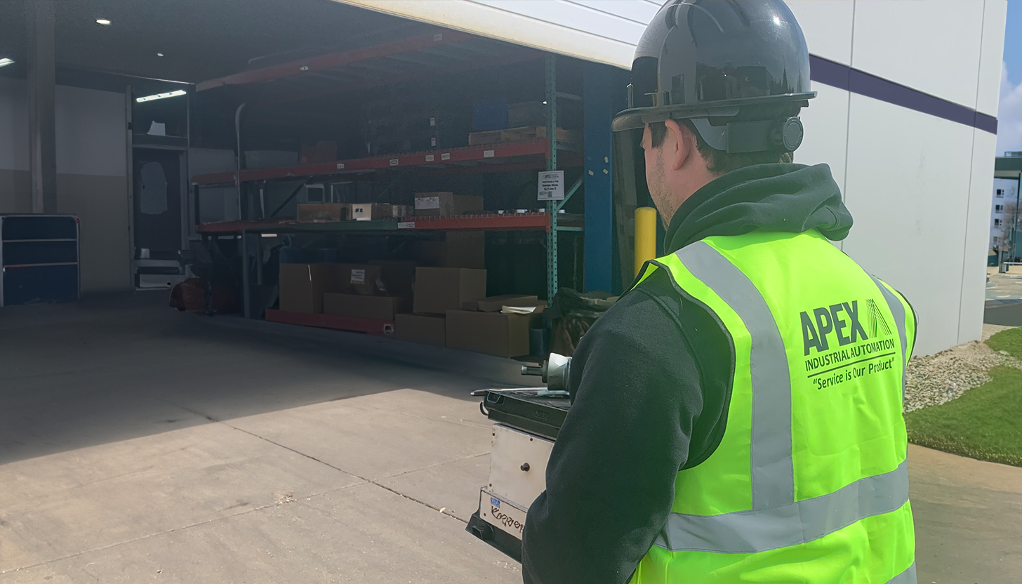Apex onsite engineer in branded safety vest and helmet arriving at a customer location for onsite repair & maintenance.