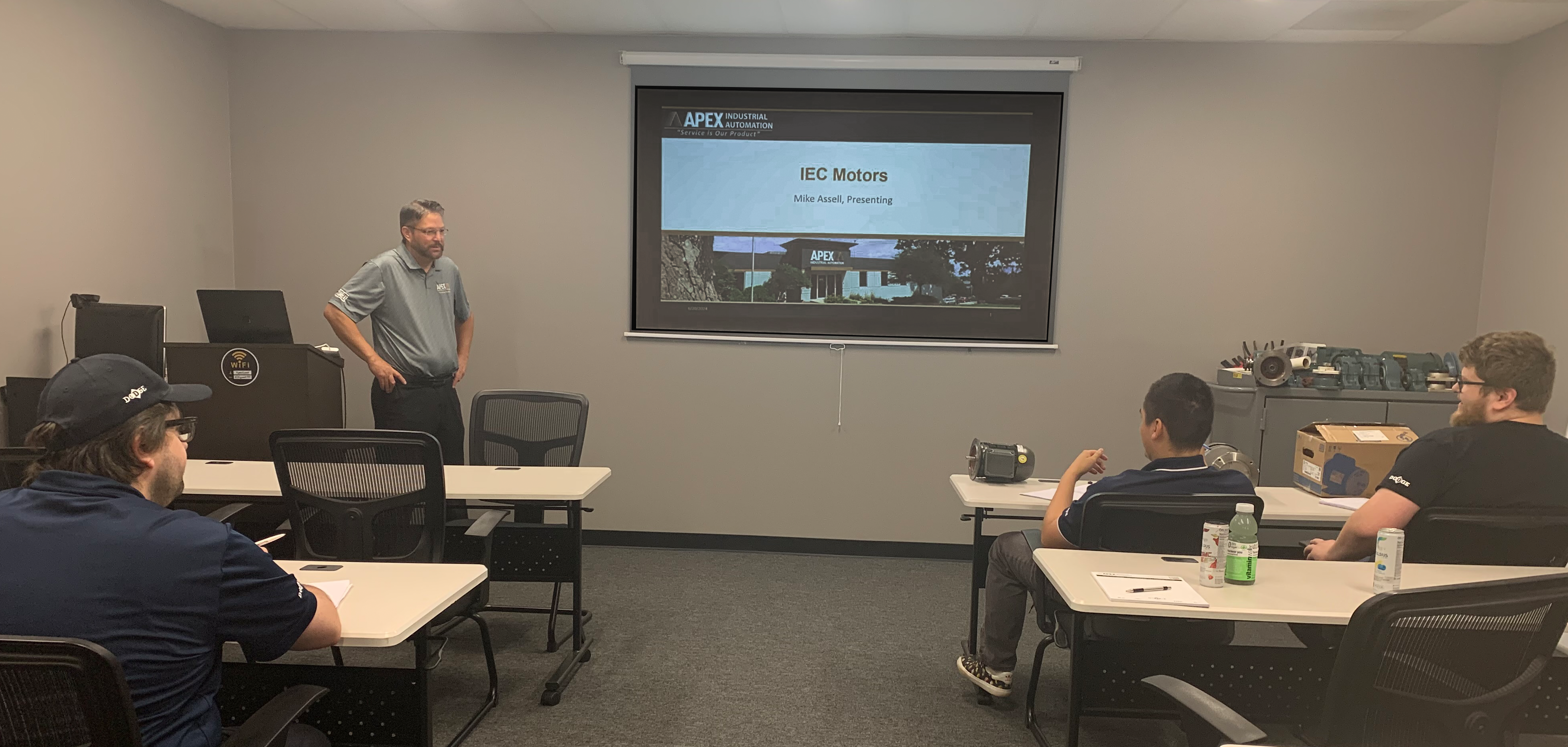 Apex Industrial Automation’s IEC motor training session in a corporate classroom, led by the VP of Sales and Marketing.